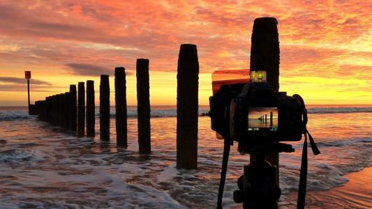 摄影师在海边拍日落