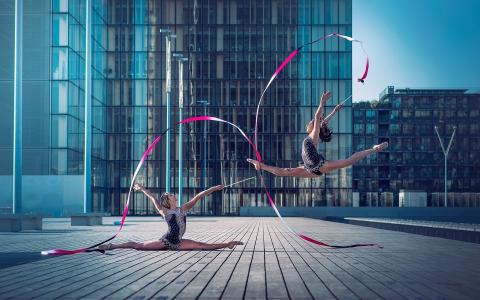 用丝带在摩天大楼前的广场上的体操运动员