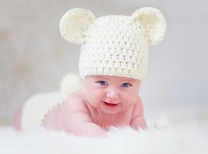 蓝眼睛的婴儿在一个白色的针织的帽子，耳朵