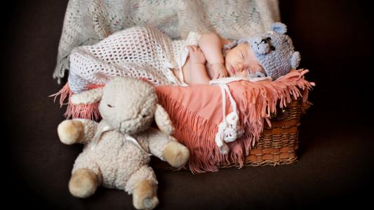 一个睡着的婴儿在一个有毛绒玩具的滑稽帽子里