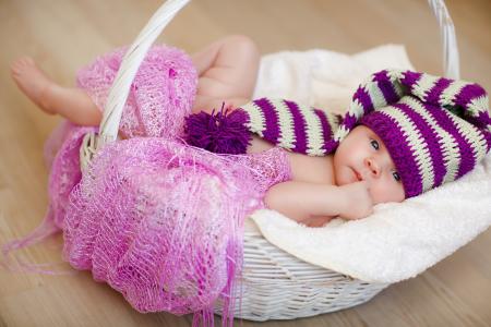 戴着漂亮的针织帽的婴儿躺在篮子里