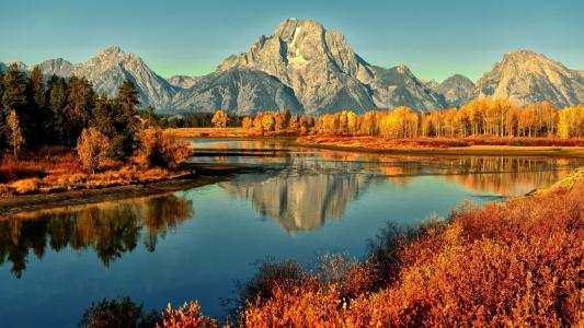 山上和秋天的树木在河中反映出来
