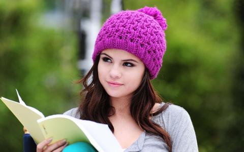 一个戴着淡紫色帽子的女孩读一本书