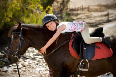 小女孩戴着头盔骑小马