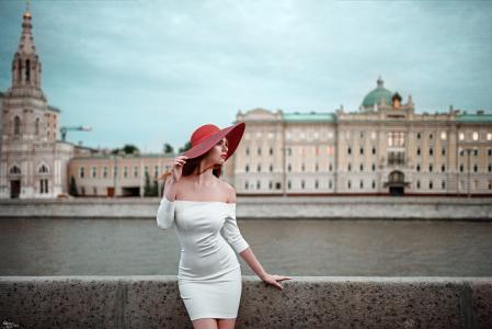 一个白色的裙子和一个红色的帽子，在江边的女孩