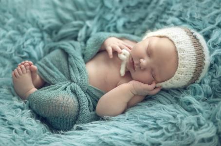 婴儿的乳房睡在绿色的皮毛毯上
