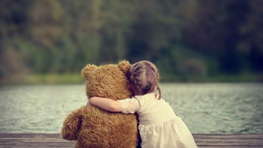 女孩正坐在一个泰迪熊的拥抱