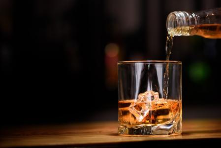 威士忌从一个瓶子倒入一杯冰
