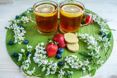 两杯茶与柠檬草莓，蓝莓和姜切片的桌子上