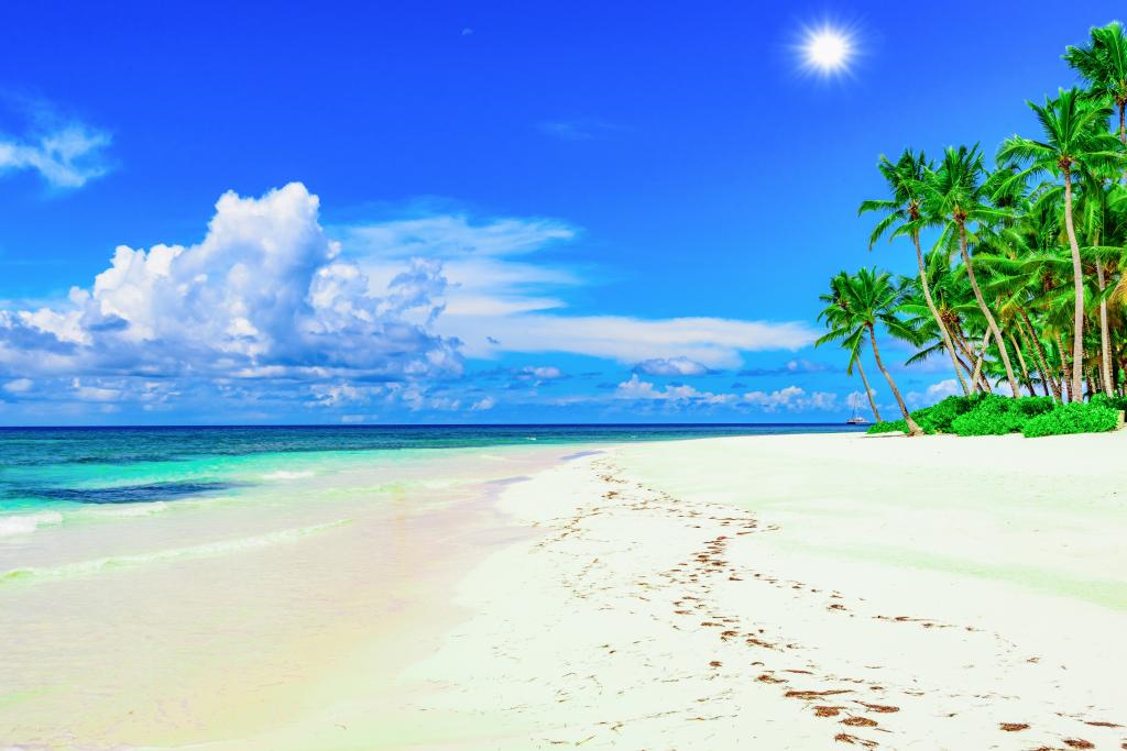 在美丽的蓝天下的热带海滩上的白色沙滩上的脚印