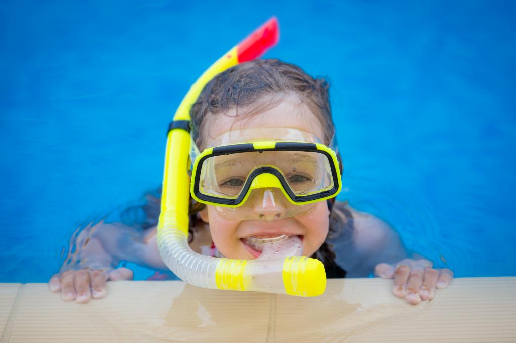 一个戴着面具的小女孩在游泳池里游泳