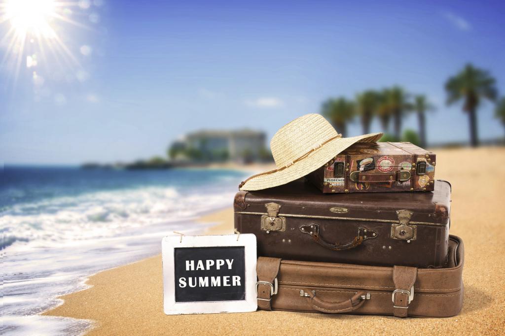 在夏天，手提箱和一顶白帽子躺在黄沙上