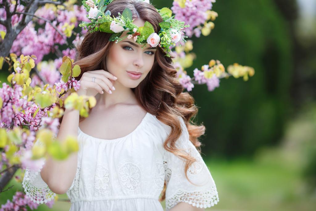 美丽温柔的棕发女人穿着白色连衣裙与她头上的花环