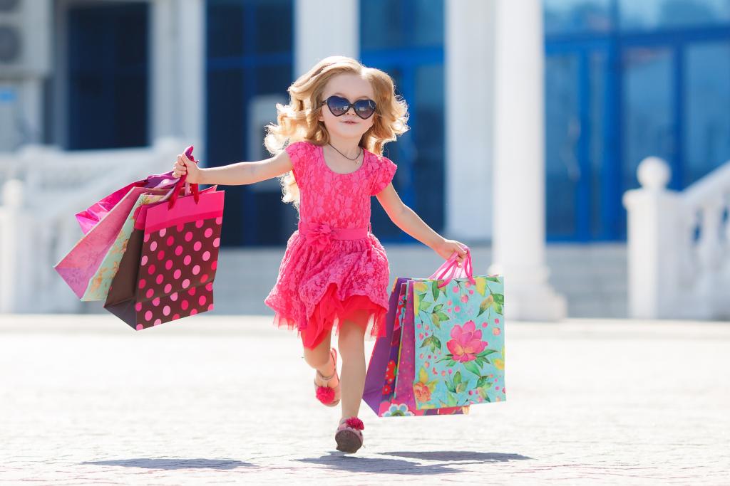 穿粉色连衣裙的小女孩正在从商店购物