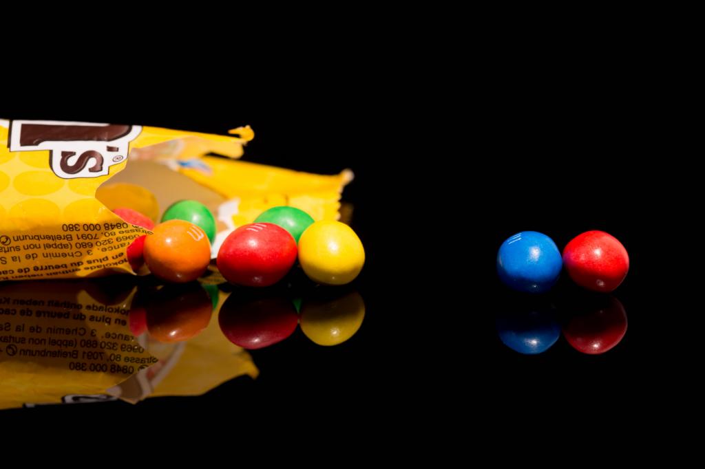 Разноцветные конфеты  M&m's отражаются в черной поверхности стола 
