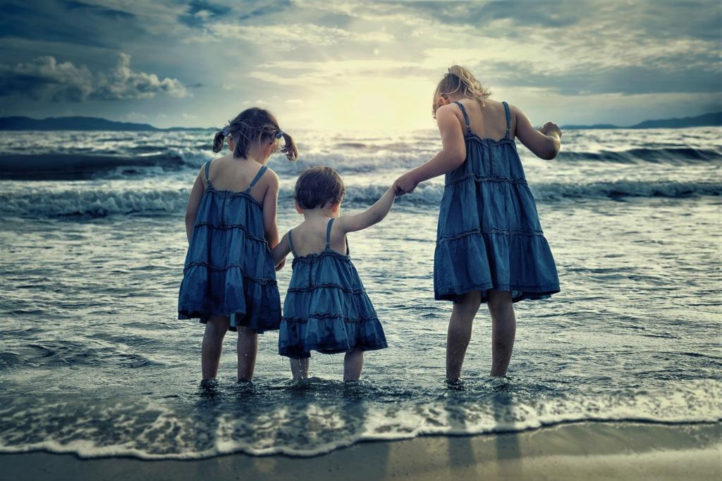 三个小女孩站在海边的水中