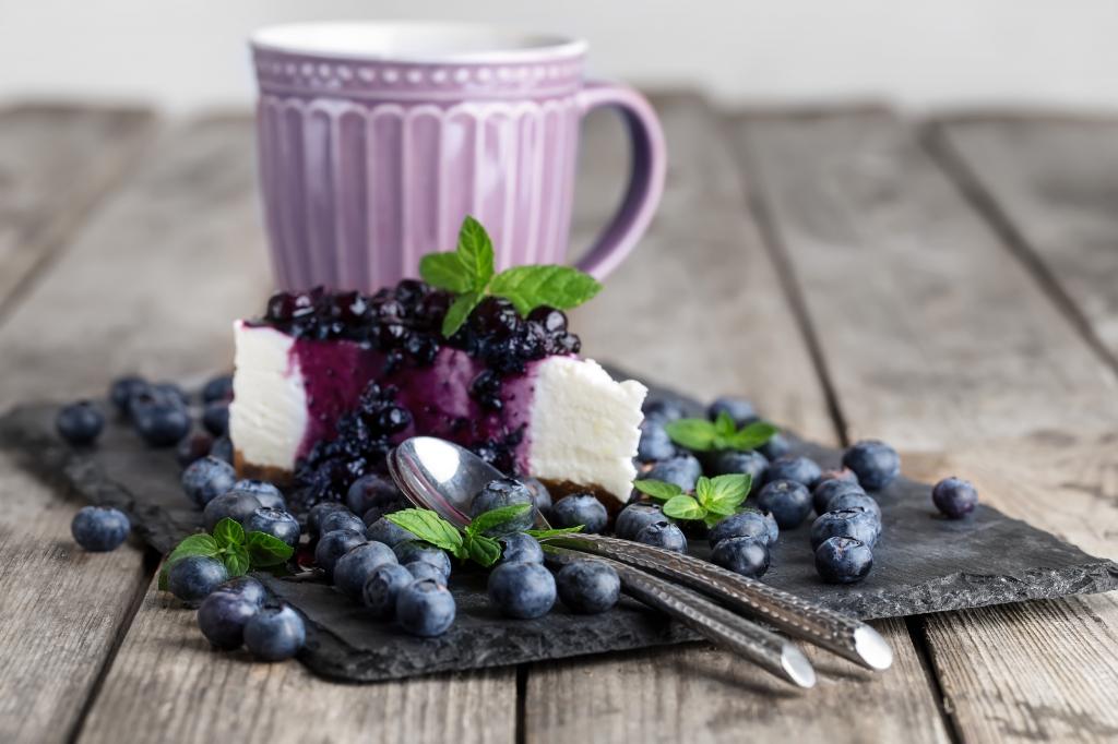 蓝莓芝士蛋糕与新鲜浆果躺在一张桌子上一杯