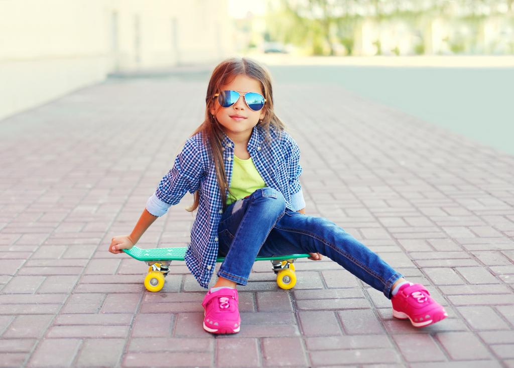 太阳镜的女孩坐在滑板上