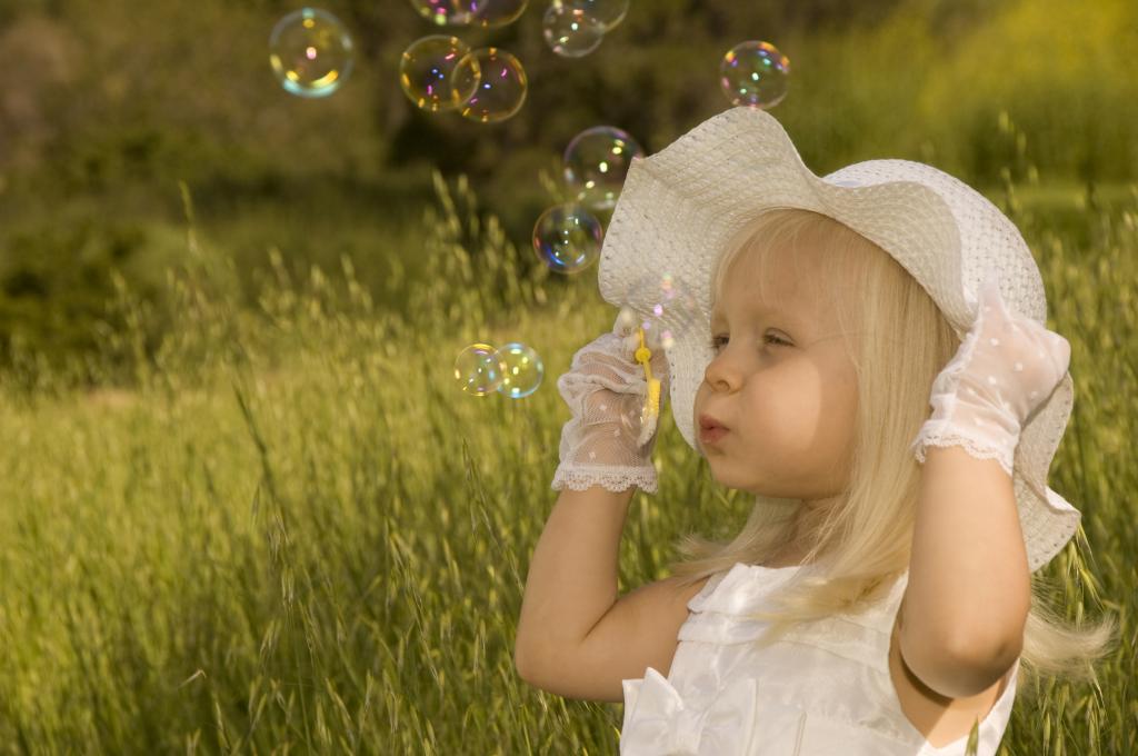 一个戴着大白帽子的小女孩发射肥皂泡