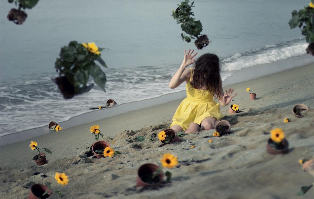 模型在一件黄色的连衣裙之间在海滩上的花朵