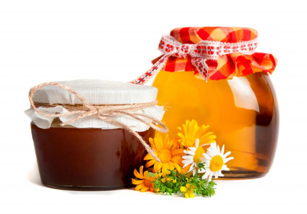 两罐蜂蜜与白色背景上的花朵