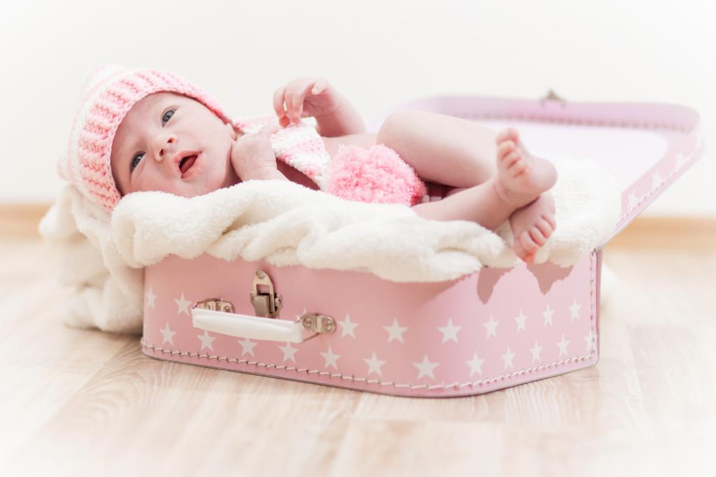 一个可爱的婴儿躺在粉红色的手提箱里
