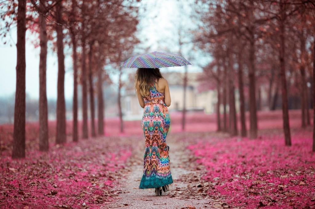 穿着漂亮衣服的雨伞下的女孩沿着胡同走