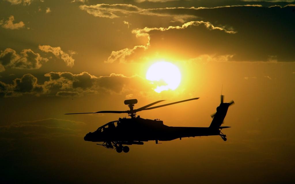 直升机AH-64阿帕奇在太阳的背景下