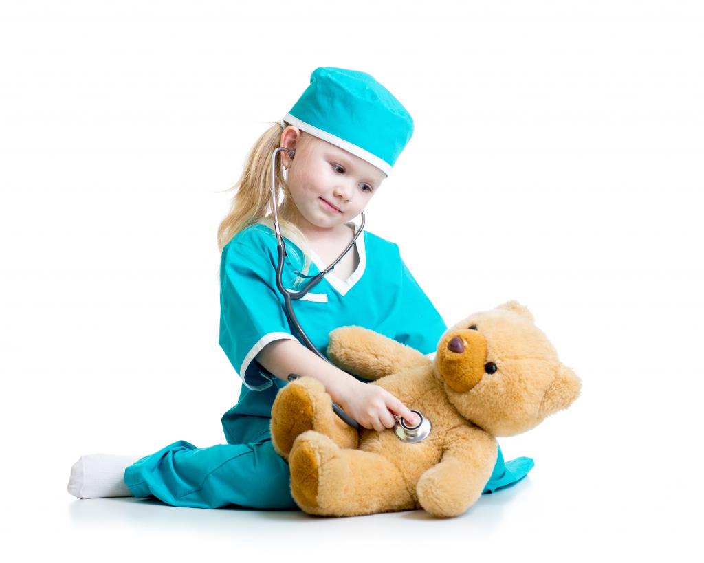 作为医生打扮的小女孩对待一只泰迪熊