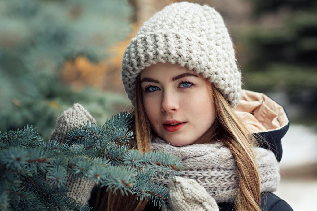美丽的年轻蓝眼睛的女孩在一个云杉分支在冬天
