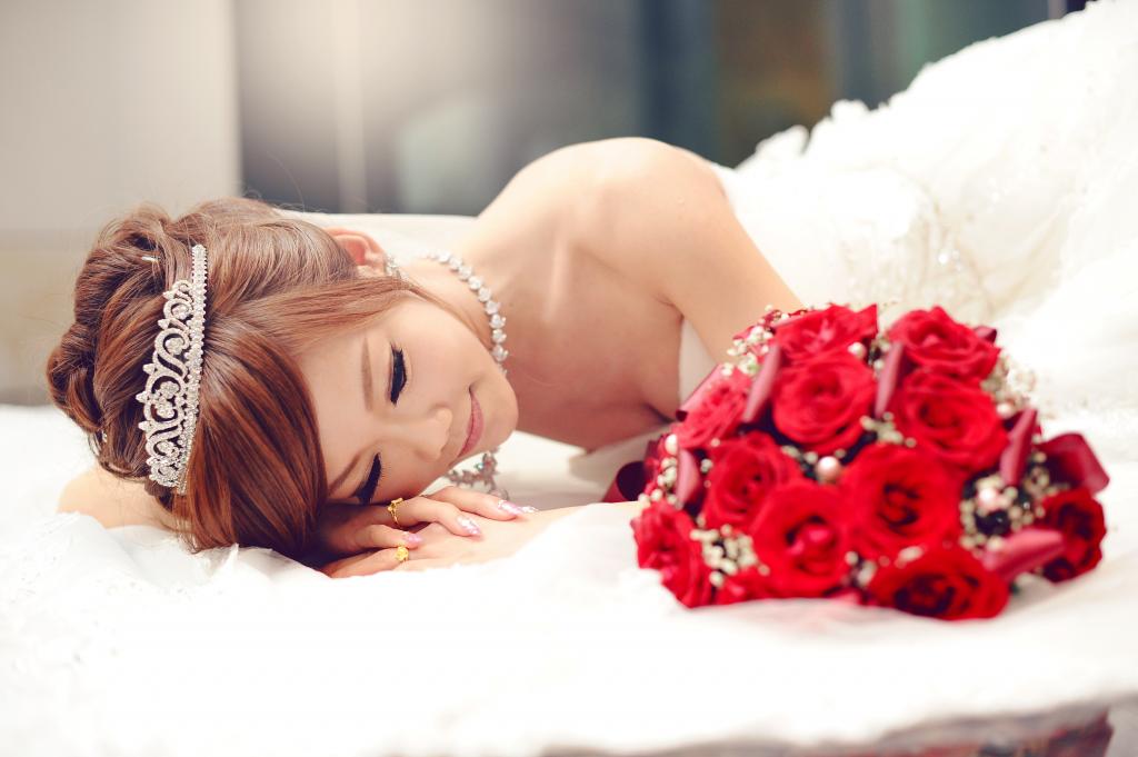 美丽的亚洲女孩穿着婚纱与一束红玫瑰