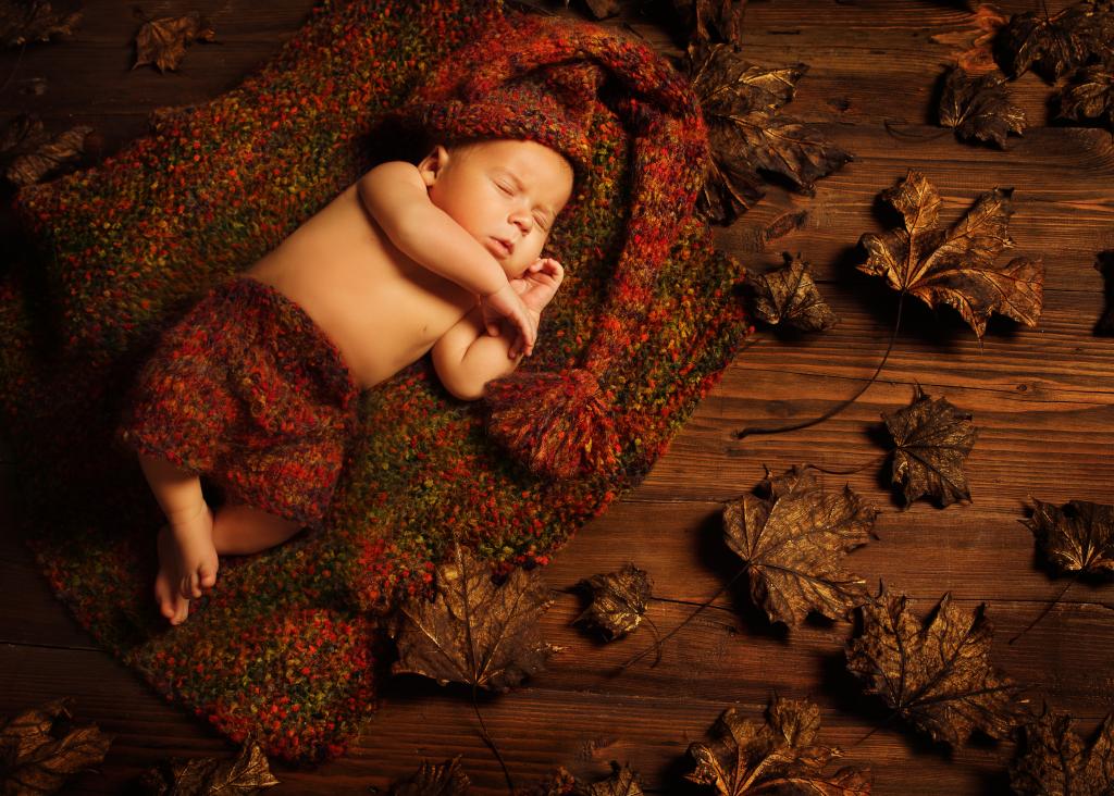 一个小孩子睡在地板上的干燥叶子针织西装