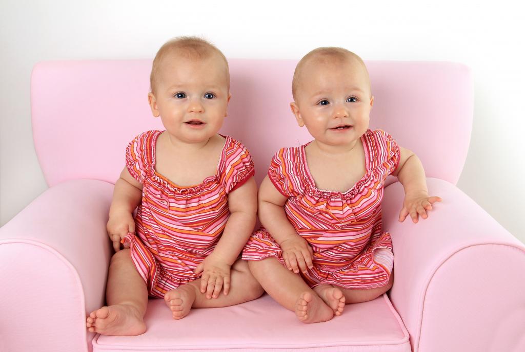 两个可爱的小女孩坐在粉红色的沙发上