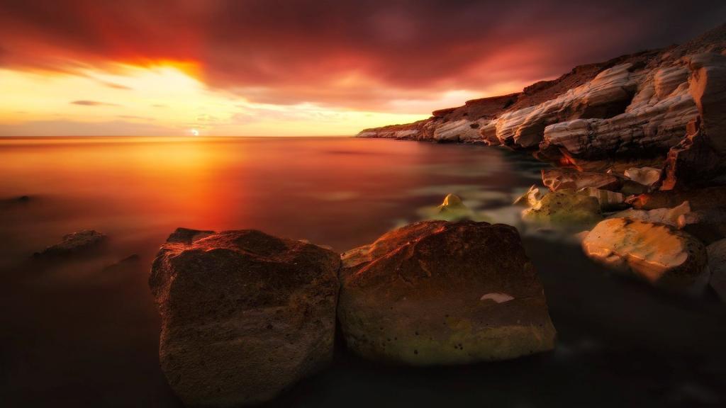 日落时在海滩上的两个大石头