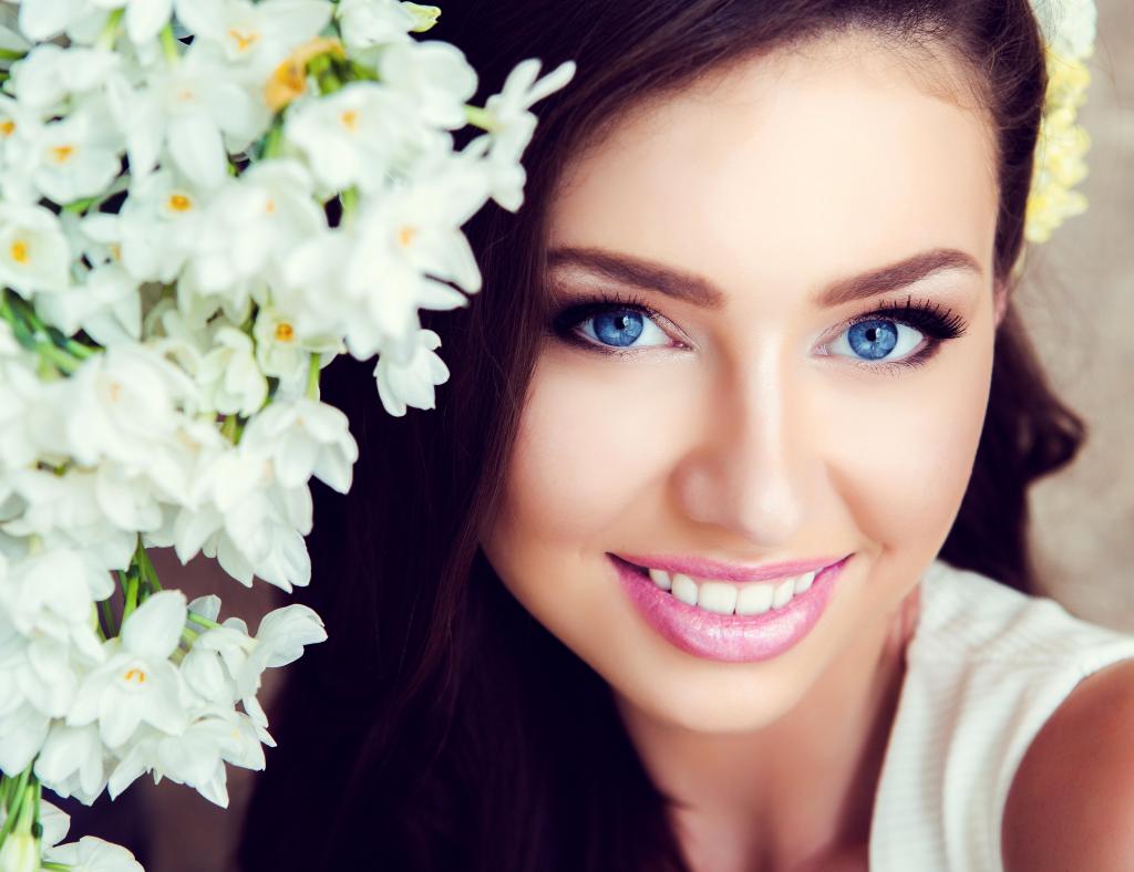 美丽的蓝眼睛的黑发女郎，娇嫩的花朵，白色的兰花