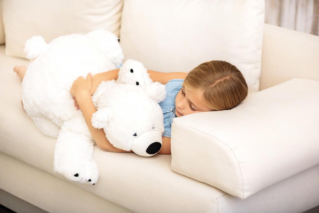 小女孩睡在沙发上的白色泰迪熊