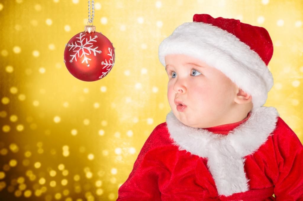 圣诞老人服装的小男婴看圣诞球