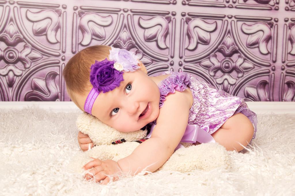 紫色西装的美丽的小女孩与玩具熊