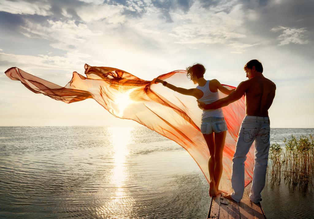爱在日落时分在海边散步的年轻夫妇