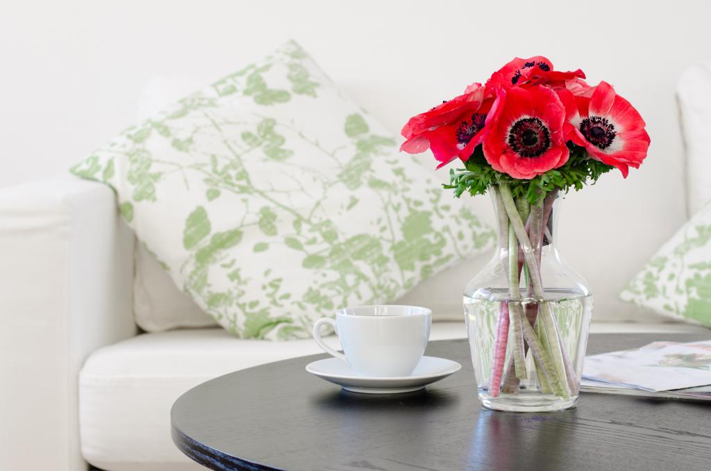 在一个白色杯子的桌子上的花瓶里的红色海葵的花束