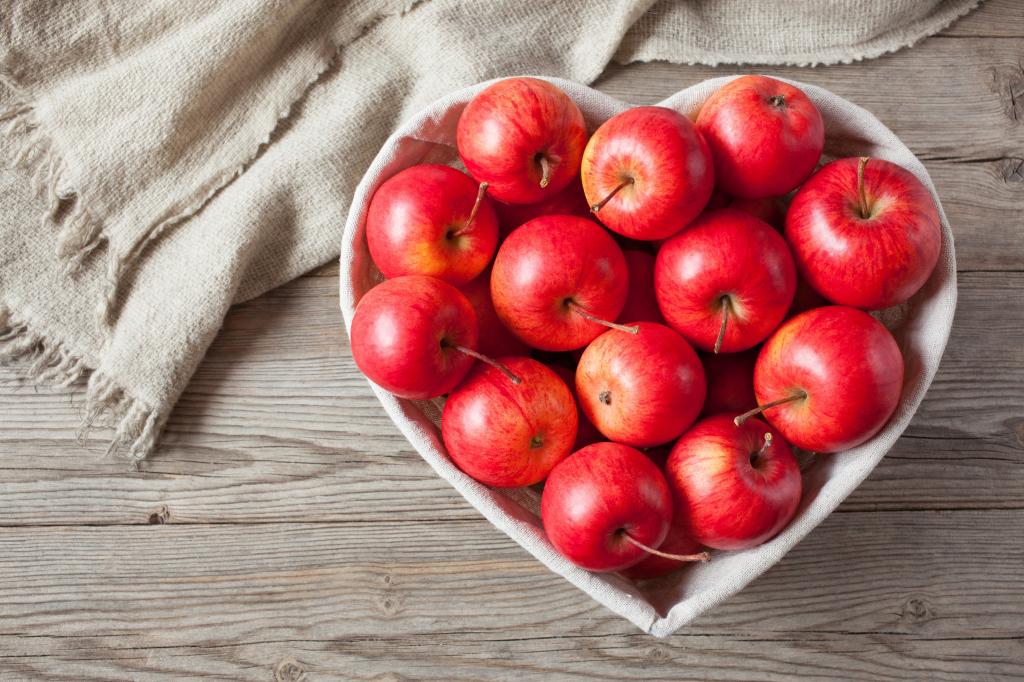 美丽的红苹果，在一个盘子里，在桌子上的一颗心的形状