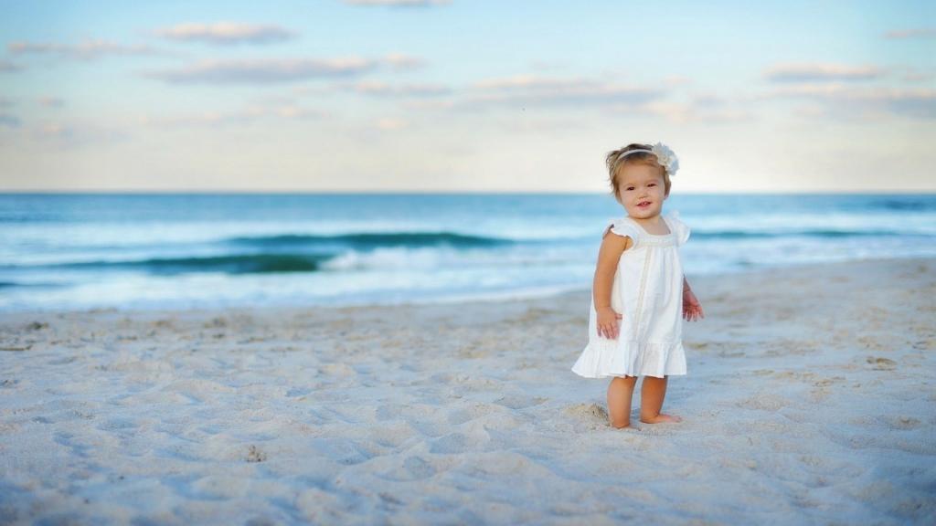 一个穿着白色连衣裙的女孩在沙滩上的沙子
