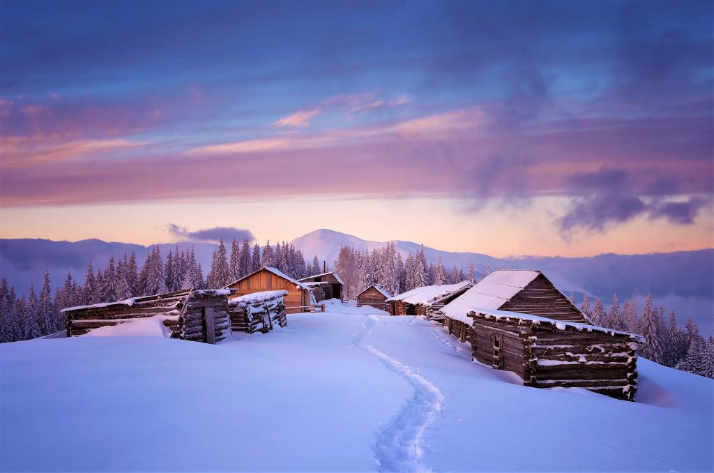 木制的房子在冬天的山背景上覆盖着雪