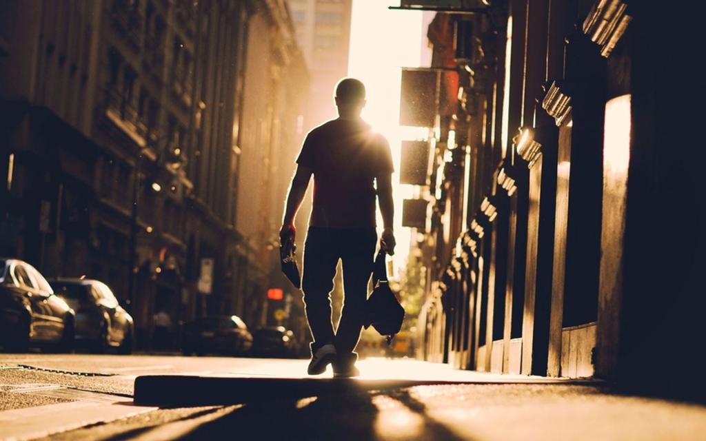 一个男人走向街道朝向太阳
