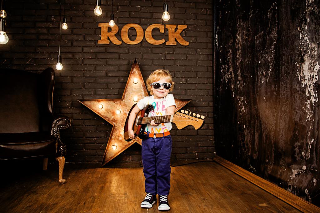时尚眼镜的小男孩与一把吉他