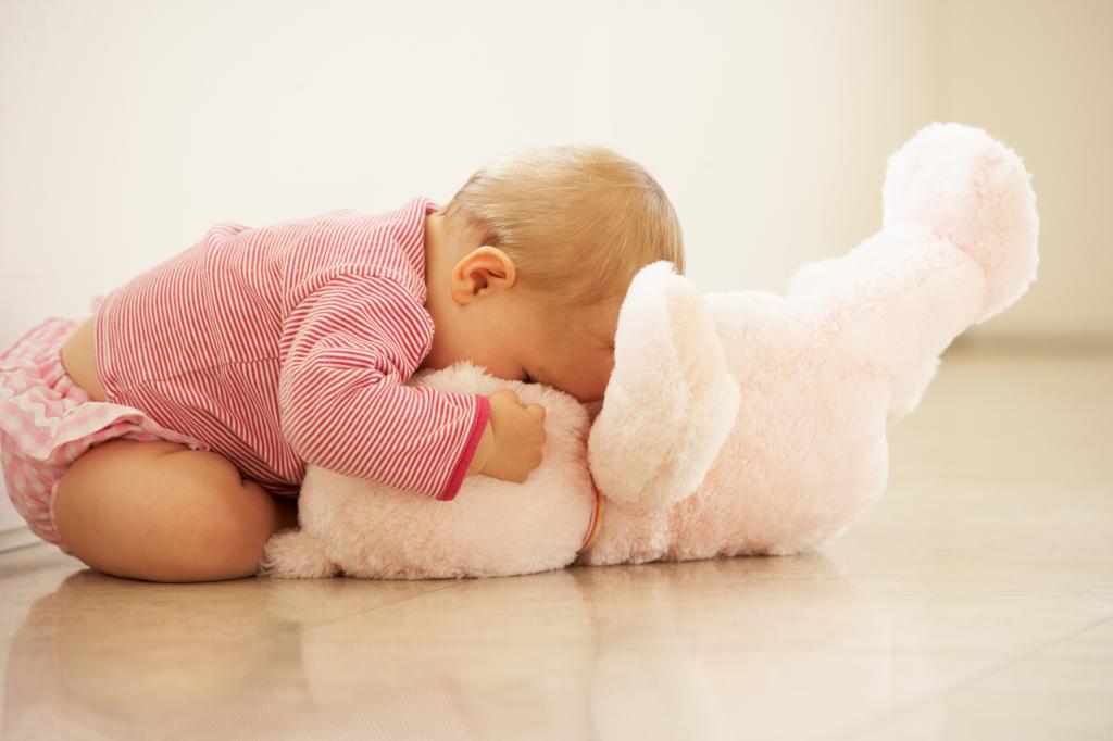 一个小孩正在玩一个粉红色的玩具熊