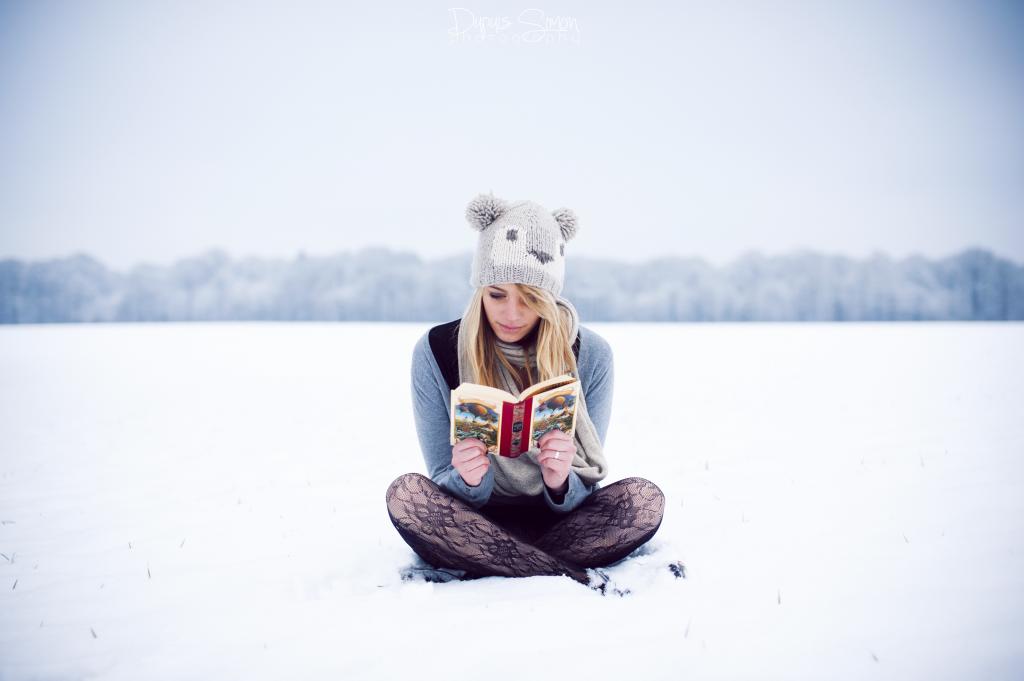 坐在雪地上读书的女孩