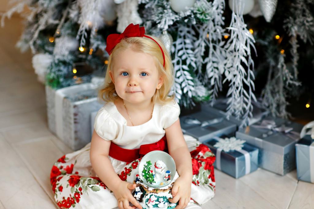 小金发女孩坐在圣诞树下的礼物