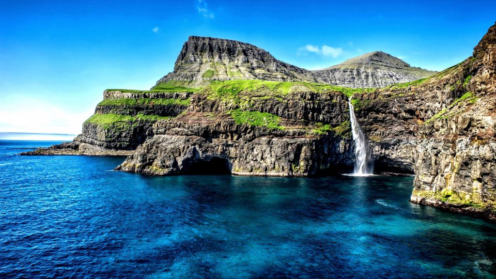一个小瀑布从峭壁流入夏威夷的海洋