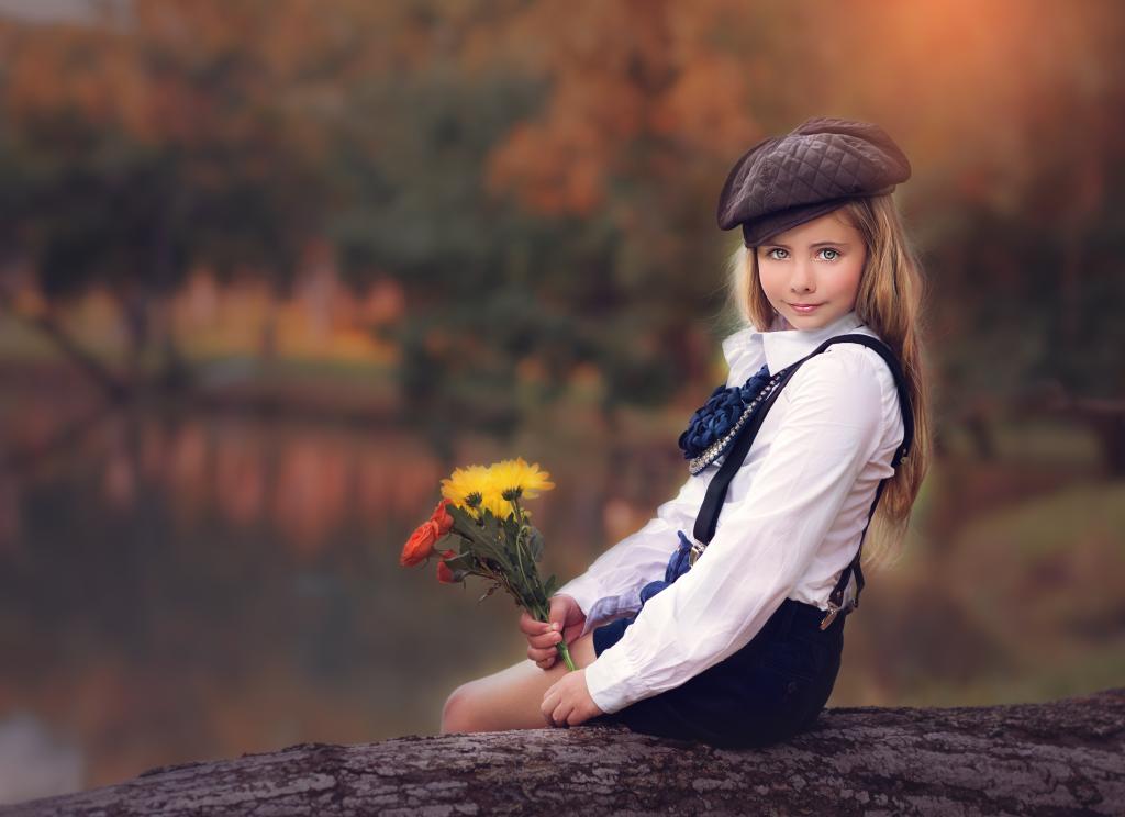 美丽的女孩在一束花在手中的帽子坐在一棵树上